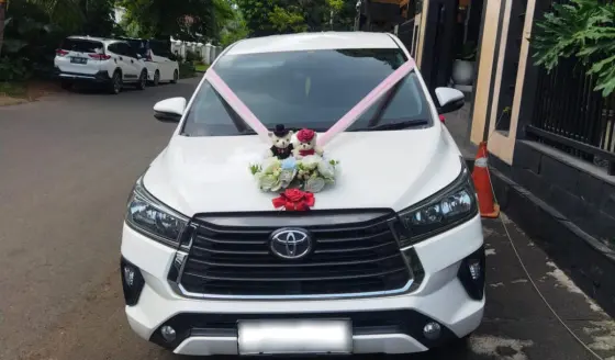 Innova Reborn putih dihias pita dan bunga untuk mobil pengantin