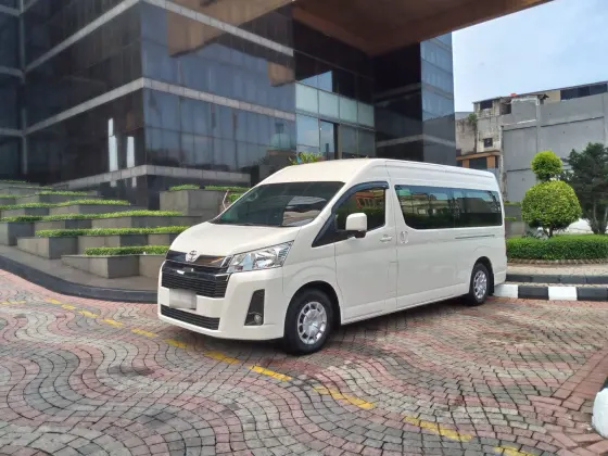 Toyota Hiace Premio putih di depan gedung perkantoran
